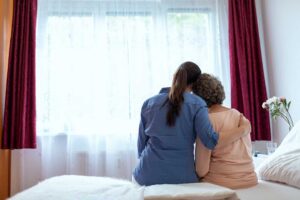 Assisted living staff member helping an older adult with daily activities in a comfortable residential setting.