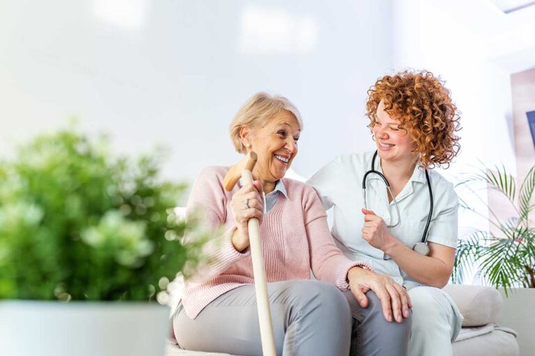 Resident using a hallway handrail while staff member checks an emergency call system
